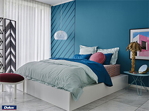 Blue feature wall white ceiling with hanging lamp and artwork and blue pillow with plant tile floor